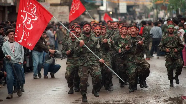 Integrantes do Hezbolá segurando armas e bandeiras