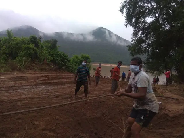 బోటును లాగుతున్న బృందాలు