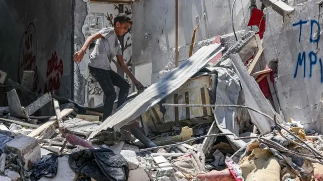Un niño palestino caminando sobre los restos de una vivienda