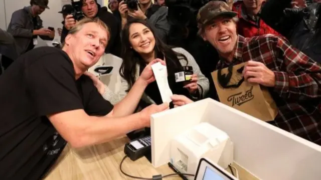 Nikki Rose (hagati) na Ian Power (iburyo) babaye aba mbere baguze urumogi byemewe n'amategeko muri Canada kuri uyu wa gatatu