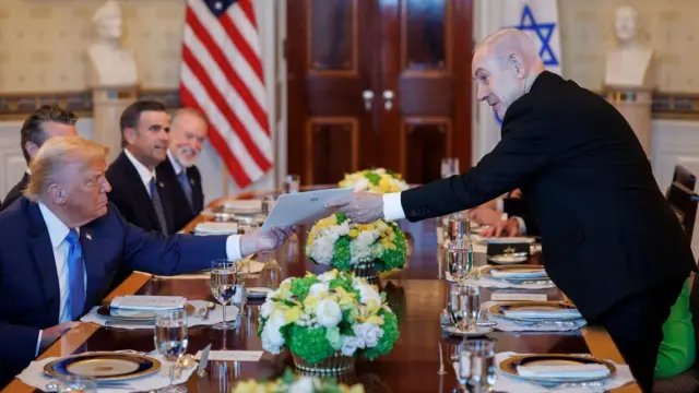İsrail Başbakanı Netanyahu, 7 Temmuz 2025'te Beyaz Saray'daki akşam yemeği sırasında Başkan Donald Trump'a bir zarf uzatırken. 