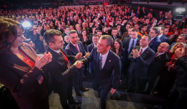 Özgür Özel, başkanlık seçimi sonrası konuşma yapmak için kürsüye çıkıyor, insanların ellerini sıkıyor