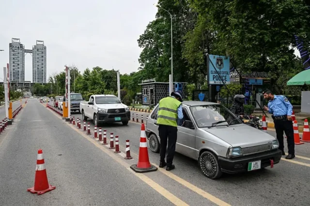 دو مامور پلیس در حال کنترل و نظارت رفت و آمد خودروها در خیابانی که دارای جایگاه ایست و بازرسی است