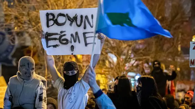 26 Mart'ta Ankara'da yapılan gösteride yüzleri kapalı gençlerden biri Göktürk bayrağı sallıyor. 