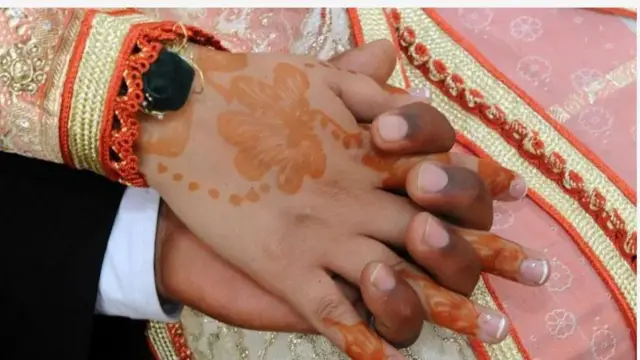 Aworan ọwọ ọkọ ati iyawo lọjọ igbeyawo wọn. Ọwọ iyawo pupa, ti ọkọ dudu. Iyawo tọ laali pupa sọwọ,o si to awọn ẹṣọ si ọrun ọwọ rẹ. 