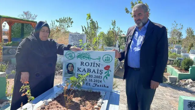 Bir kadın ve erkek mezar taşının başında