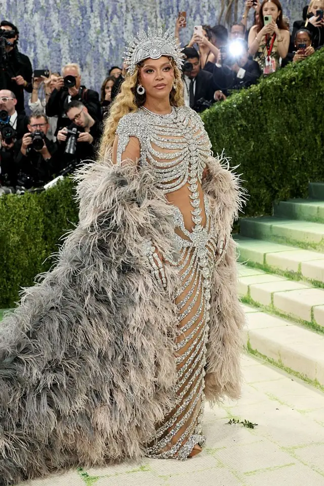 Beyonce, iskelet desenli işlemeli bir elbise ve devasa bir tüy pelerin giyiyor.
