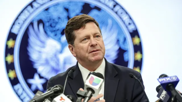 Džej Klejton, državni tužilac Sjedinjenih Država za Južni okrug Njujorka, govori na konferenciji za novinare u tamnom odelu, okružen mikrofonima američkih medija, sa pečatom Ministarstva pravde iza sebe.