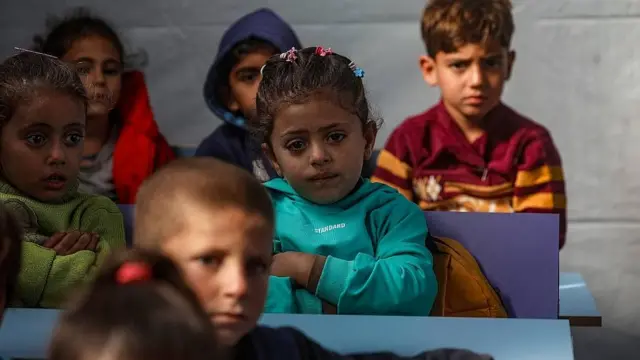 Niños pequeños sentados en una escuela temporal en una tienda de campaña.