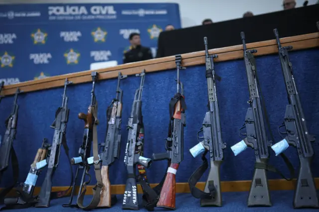 Fuzis apreendidos enfilerados durante conferência de imprensa após operação em comunidades do Rio de Janeiro