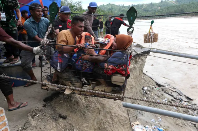 Warga menggunakan kabel baja yang untuk menyeberangi Sungai Juli pascaputusnya Jembatan Juli di jalan lintas Bireuen - Takengon, Aceh, Selasa (2/12/2025). Kabel baja yang didesain khusus relawan bencana menjadi sarana penghubung untuk memobilisasi warga dan barang sejak putusnya jembatan Juli pada 26 November 2025 akibat banjir luapan Sungai Peusangan. 