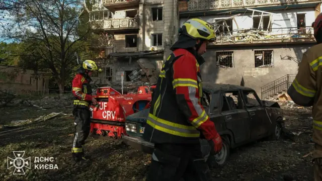 Двоє пожежників на фоні зруйнованого будинку