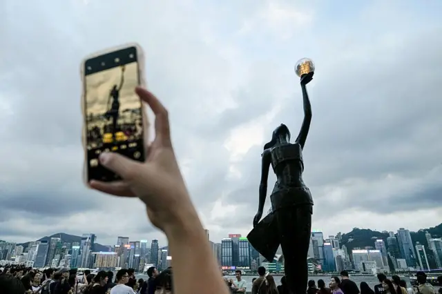 2025年8月23日，游客在香港星光大道海滨长廊为香港电影金像奖雕像拍照，