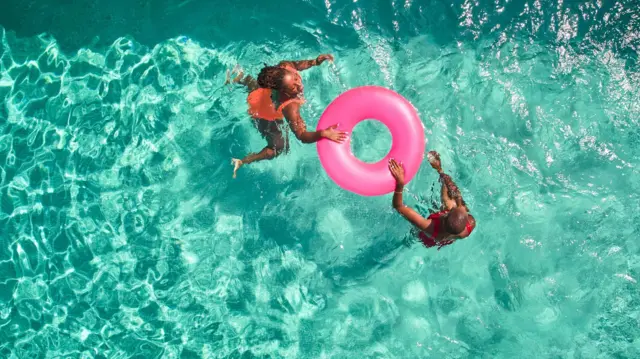 Bir anne ve çocuğu havuzda yüzüyor.