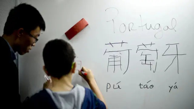 Чоловік і хлопець обличчям до білої дошки, на якій написані слова різними мовами