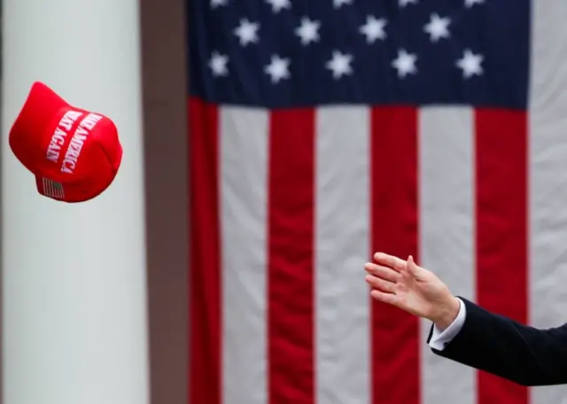 دستی که در حال تلاش برای رسیدن به یک کلاه ماگا است
