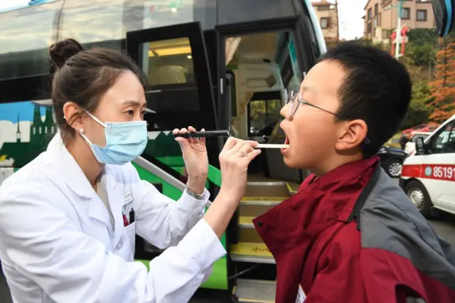 চীনে এক ছাত্রকে পরীক্ষা করছেন চিকিৎসক।