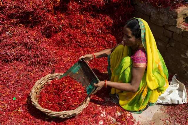 Seorang pekerja memilah pecahan kaca untuk digunakan kembali di pabrik gelang di Firozabad.