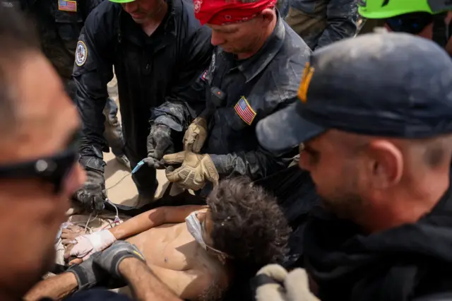 Un miembro de un equipo de rescate de EE.UU. ayuda a una persona que había quedado atrapada bajo los escombros de un edificio tras los terremotos que azotaron el país, en La Guaira.