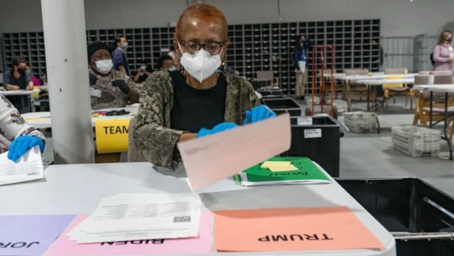 2020'de Georgia eyaletindeki bir oy sayım merkezinde maskeli bir kadın belgeleri tutuyor