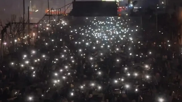 جمعی از معترضان دی ماه در یکی از خیابان های اصلی شهر تهران همزمان با تاریکی عمدی خیابان ساعاتی پیش از سرکوب خونین چراع های گوشی تلفن همراه خود را به نشان اعتراض روشن کرده‌اند