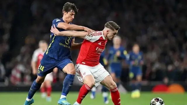 Atletico Madrid player wear dark blur jersey while Arsenal player wear Red jersey on white shorts as dem dey drag to reach di ball.