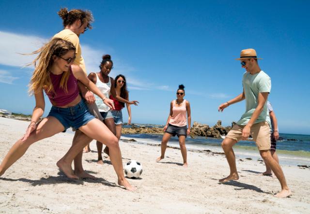 Amigos jugando fútbol en la playa