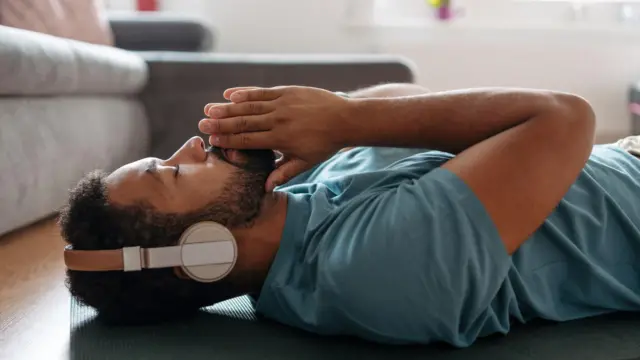 Homem ouve música para meditação e faz exercícios de respiração