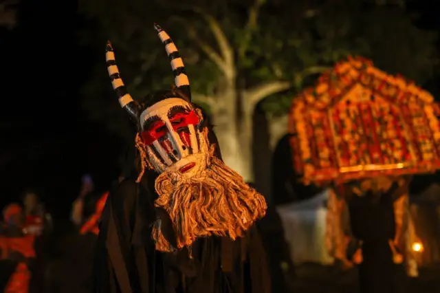 People in masks sway.