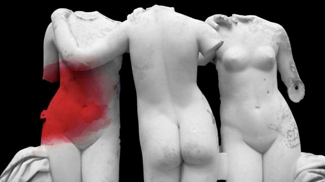 Estátuas de corpos femininos em mármore, uma delas com uma mancha vermelha na região do abdômen sugerindo dores