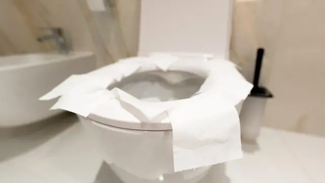 Vaso sanitário com a tampa levantada e o assento coberto de papel