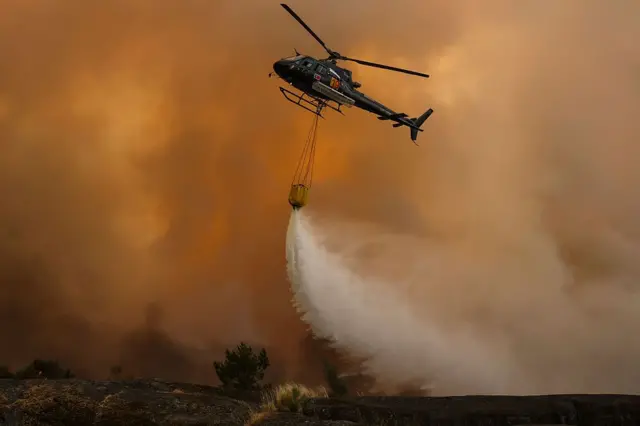 مروحية إطفاء تسقط الماء على حريق غابات في قرية كاسا دو مونتي في ترانكوسو، في 13 أغسطس/آب 2025. 