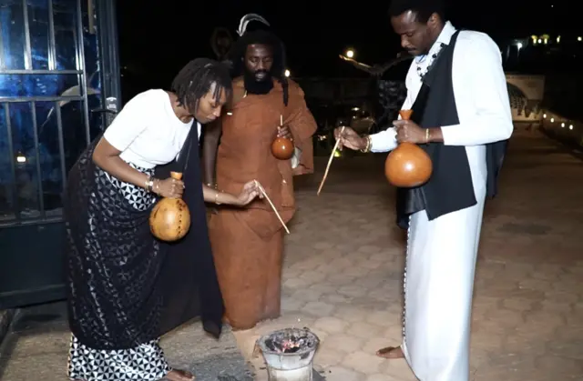 Mahoro Angel n'umugabo we, aha barimo guterekera basangira n'abakurambere babo babaha kubyo bari gusangira bacishije mu muriro