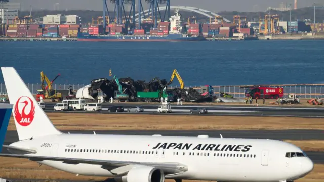 ਜਪਾਨ ਏਅਰ ਲਾਈਨਜ਼ ਦਾ ਇੱਕ ਜਹਾਜ਼ ਅਤੇ ਪਿਛੋਕੜ ਵਿੱਚ ਏਅਰਬੱਸ ਏ350-900 ਦਾ ਮਲਬਾ