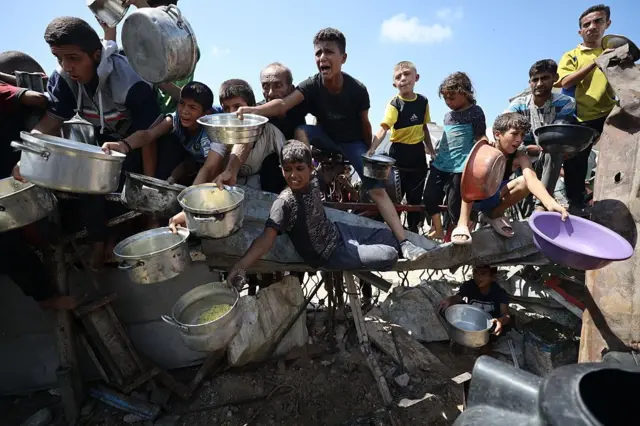 صورة بتاريخ 3 سبتمبر/أيلول في مدينة غزة، حيث أُُعلنت المجاعة ويظهر فلسطينيون يحملون أواني وأوعيةً، ويشكلون حشداً لتلقي مساعدات غذائية مقدمة من جمعية خيرية في المدينة.