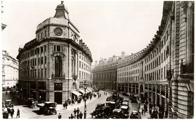 Siyah beyaz kartpostalda Regent Street'in meşhur içe bükülerek sıralanan sokağı görülüyor, yolda insanlar ve eski arabalar var. 