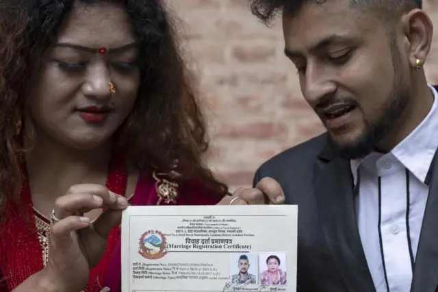 लमजुङको दोर्दी गाउँपालिकामा आफ्नो विवाह दर्ता भएपछि त्यसको प्रमाणपत्र देखाउँदै समलिङ्गी जोडी माया गुरुङ र सुरेन्द्र पाण्डे। नेपालमा पहिलो पटक समलिङ्गीहरूको विवाह दर्ता भएको हो। 