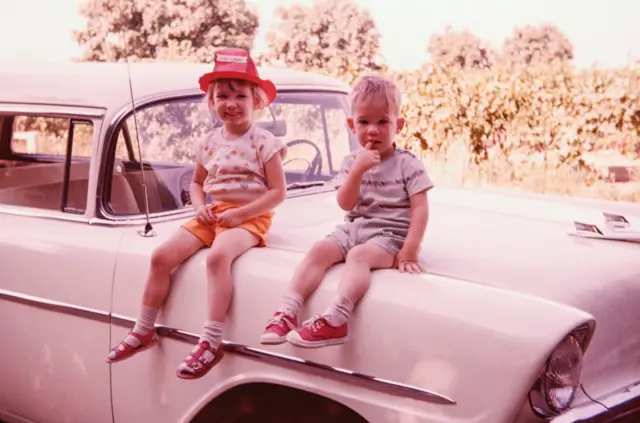 Sœur et frère sur le toit d'une vieille voiture