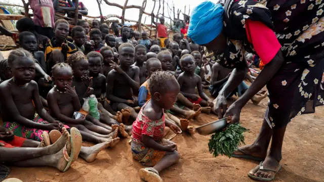نازحة تقدم الطعام لأطفال في السودان