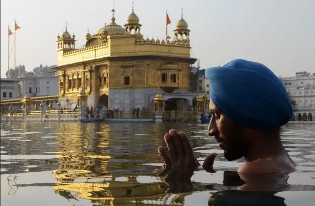 A devotee taking a dip in the pond surrounding the Golden Temple 