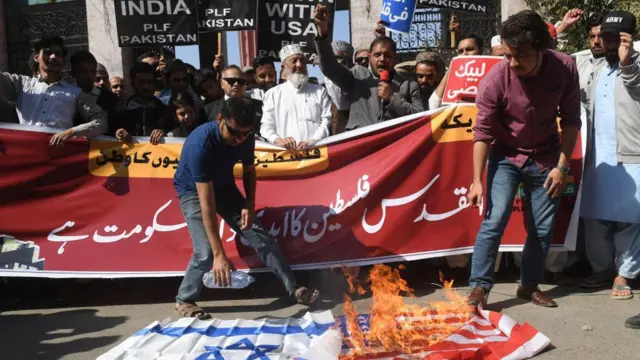 पाकिस्तान में प्रदर्शनकारी इसराइल और अमेरिकी झंडे को जलाते हुए