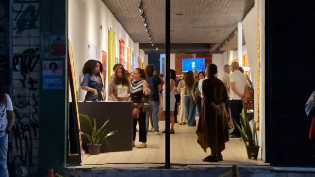 Imagen de la entrada a un espacio con una puerta de cristal, a través de la cual se pueden ver varias personas.