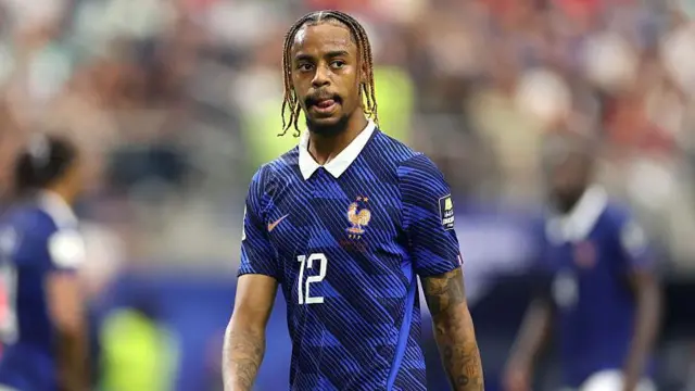 Bradley Barcola has his tongue slightly sticking out as he wears the traditional France blue national team shirt with the number 12 on its front