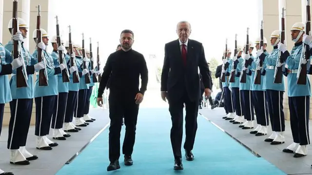 Zelenskiy Beştepe'de resmi karşılaşamada askerlerin arasından Cumhurbaşkanı Erdoğan ile birlikte yürüyor. Fotoğraf biraz alt açıdan yukarı doğru çekilmiş.