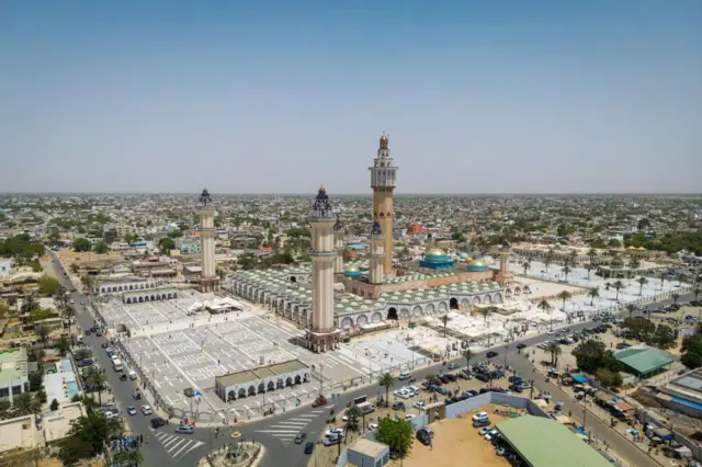 Une vue aérienne de la Grande Mosquée de Touba montre des membres de la confrérie mouride rassemblés dans la ville sainte de Touba, au Sénégal, le 21 mars 2025, pour la prière du vendredi, vingtième jour du Ramadan. Les adeptes de l'ordre soufi mouride commémorent la rencontre historique entre leur fondateur, le cheikh Ahmadou Bamba, et son premier disciple, Mame Ibrahima Fall, en effectuant un pèlerinage à Touba, située à environ 200 kilomètres de la capitale, Dakar.