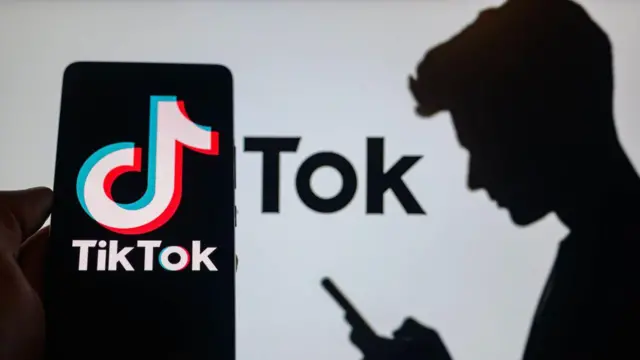 Silhueta de uma pessoa olhando para o telefone e tela de celular mostrando o logotipo do TikTok
