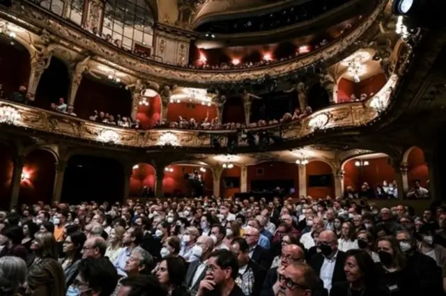 Ангела Меркелдин бул маеги "Берлинер ансамбль" деп аталган атактуу театрдын сахнасында, зал толо көрүүчүнүн катышуусунда жазылды