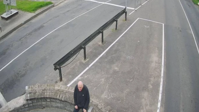 Mężczyzna siedzi na murze przy granicy