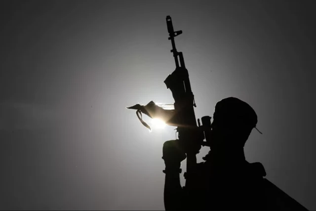 ২০২১ সালে সিনওয়ার একটি সমাবেশে ভাষণ দেওয়ার সময় একজন বন্দুকধারী মঞ্চটি পাহারা দিচ্ছে।