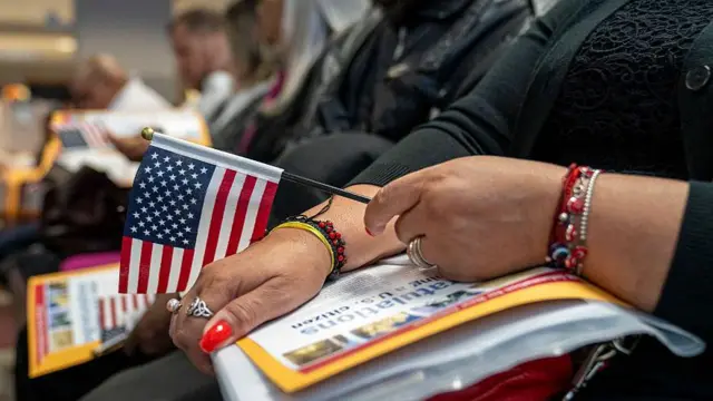 Varias personas aguardan sentadas en una ceremonia de naturalización de EE.UU.
